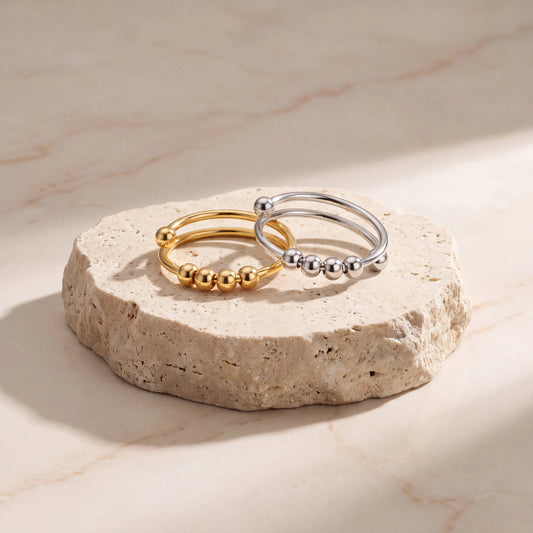 CalmOrbit gold and silver adjustable anxiety rings with movable tactile beads on travertine stone
