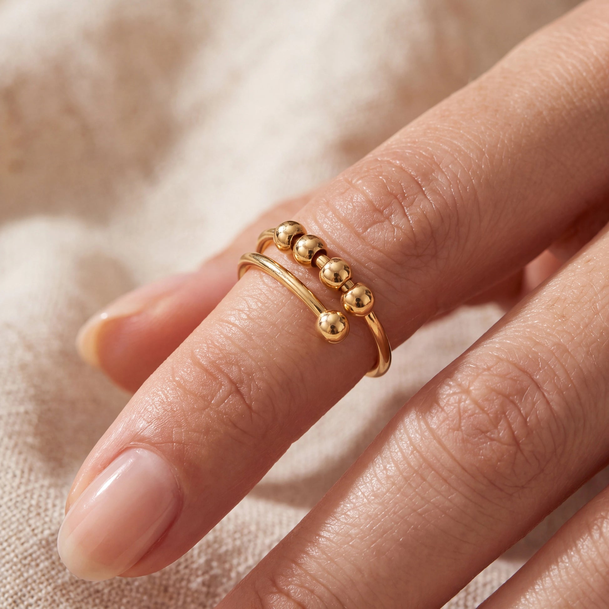Minimalist gold beaded anxiety ring worn on index finger for dermatillomania and cuticle picking relief
