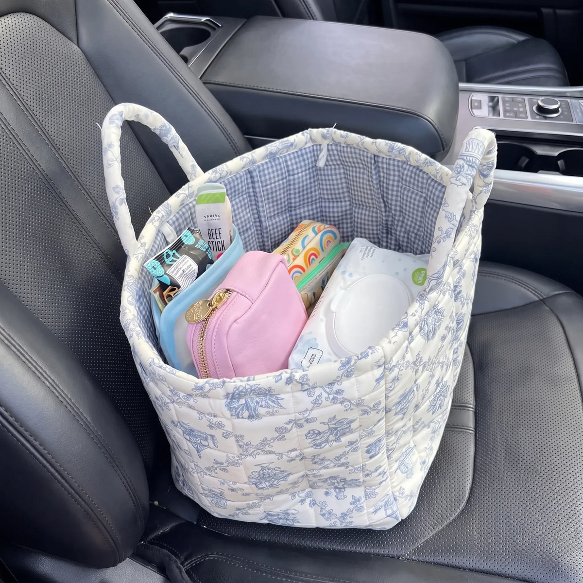 Quilted basket on a car passenger seat holding a pouch, wipes and snacks
