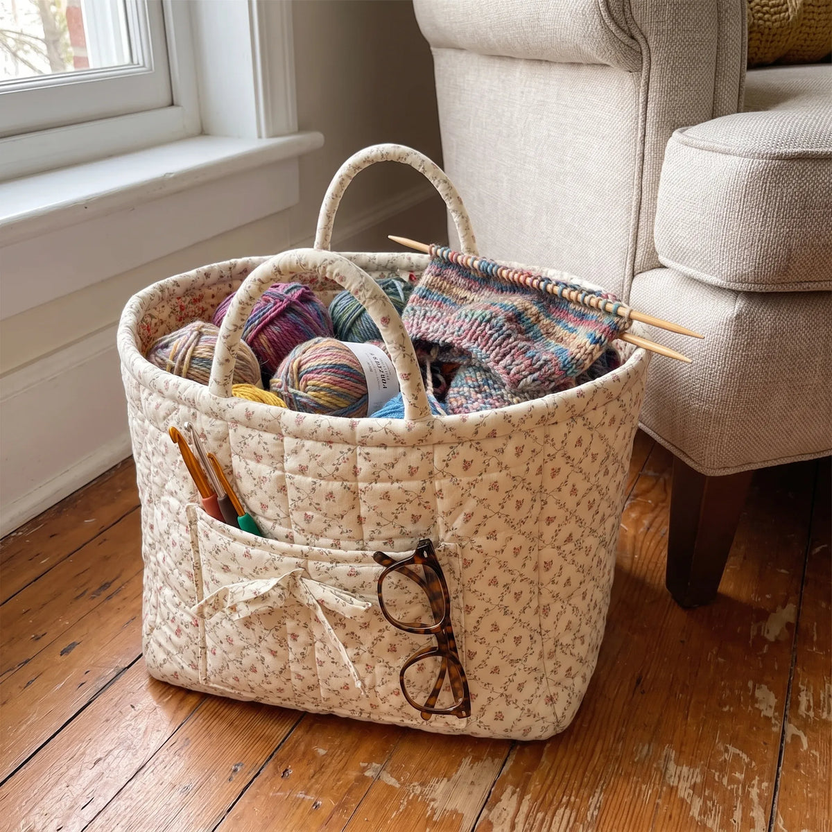 Quilted basket holding yarn and a knitting project by an armchair